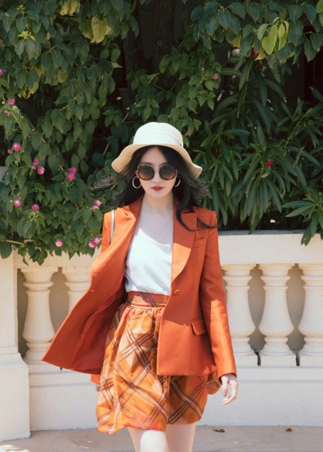 刘亦菲橙色西装搭配同色系格纹短裙，大长腿十分抢镜。
